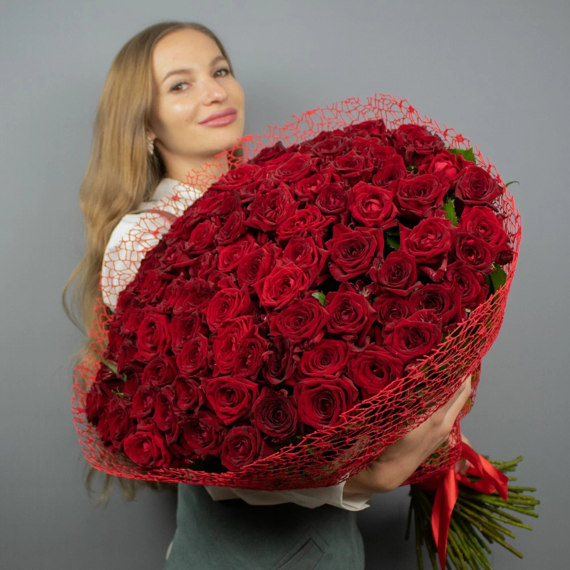Woman holding a 150 naomi red roses bouquet