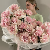 Person holding a large bouquet of pink flowers against a neutral background