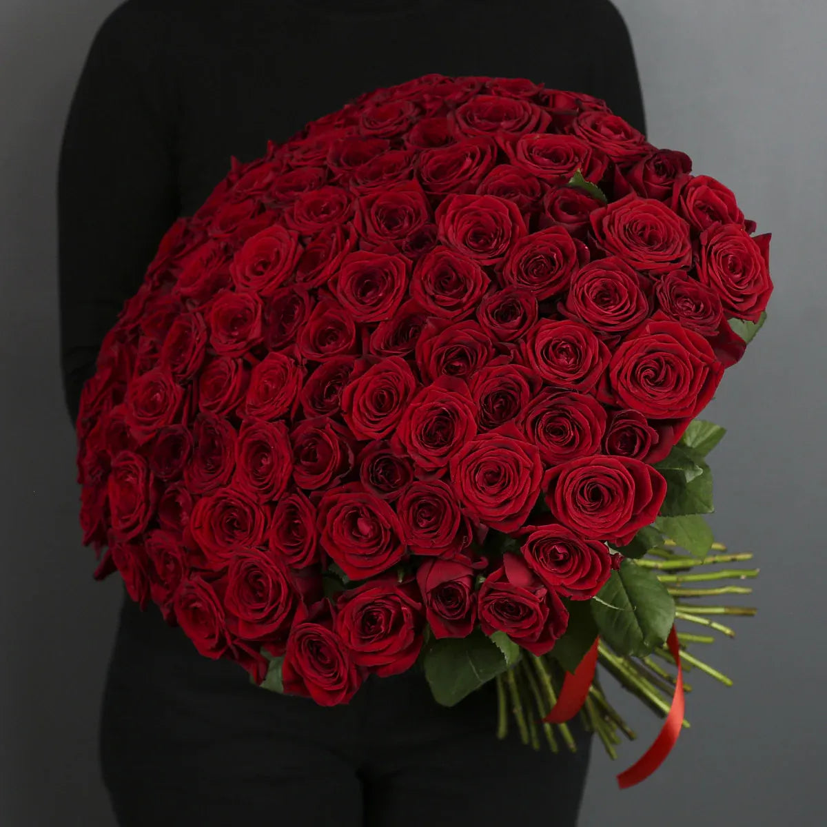 Bouquet of red roses held by a person against a dark background

